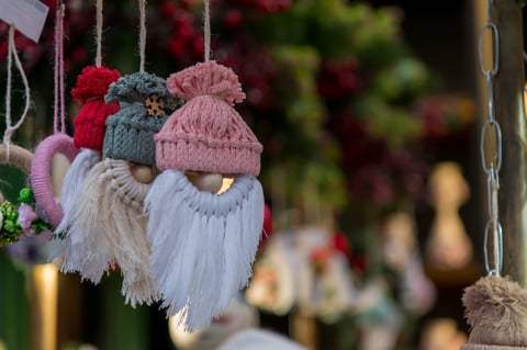 Adornos navideños coloridos de macramé con barbas esponjosas colgando en un mercado al aire libre