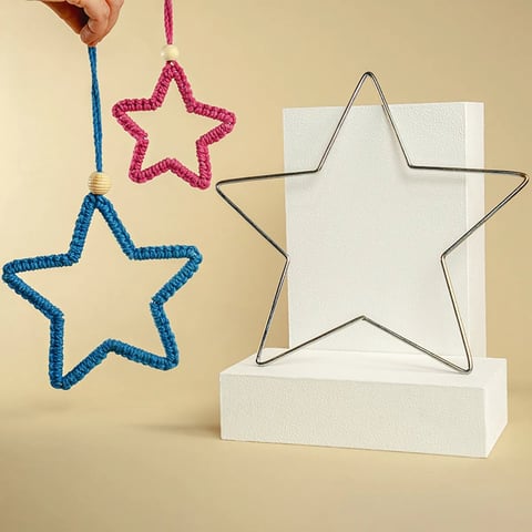 Adornos de estrella de colores y decoraciones de estrella de alambre exhibidas sobre fondo beige con bloques de papel blanco