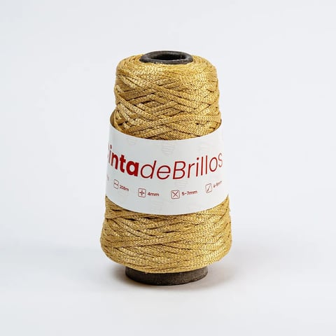 Carrete de hilo metálico dorado etiquetado Vinta de Brillos con cordel enrollado alrededor de un tubo de cartón