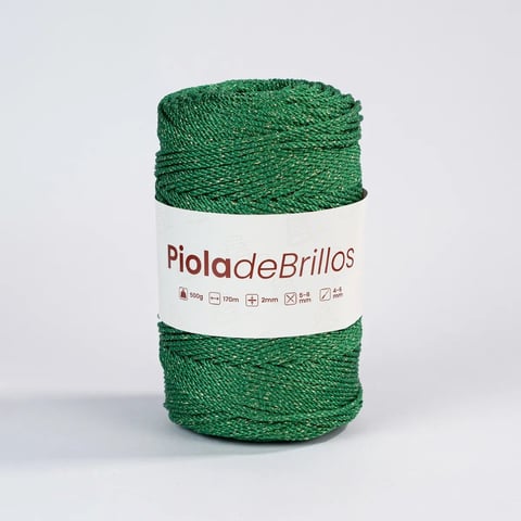 Rollo de hilo verde etiquetado Piola de Brillos con banda envolvente blanca sobre fondo claro
